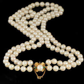 Two strand cultured pearl necklace of 0,5cms with 18kt yellow gold clasp in the shape of a flower with central pearl and emeralds.