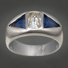 Anillo en oro blanco de 18kt con brillante central y dos piedras azules.